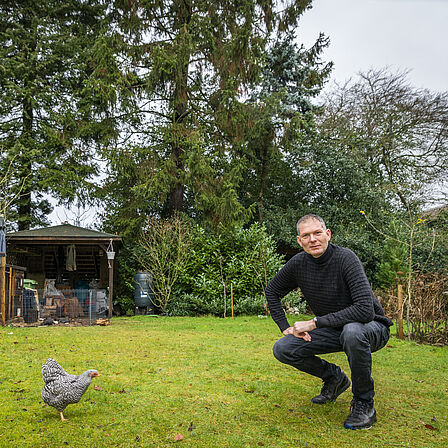 Joost Moret in zijn groene tuin bij zijn kippen