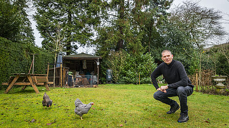 Joost Moret in zijn groene tuin bij zijn kippen