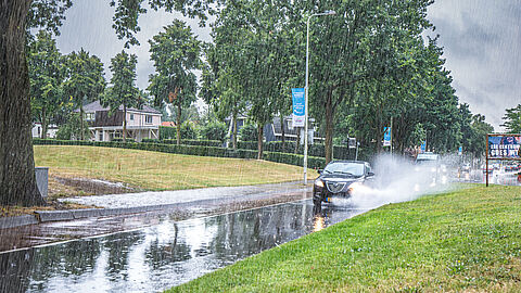 Auto's rijden tijdens hevige regenbui door plassen water