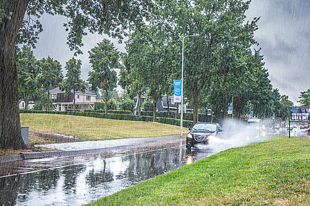 Auto's rijden tijdens hevige regenbui door plassen water